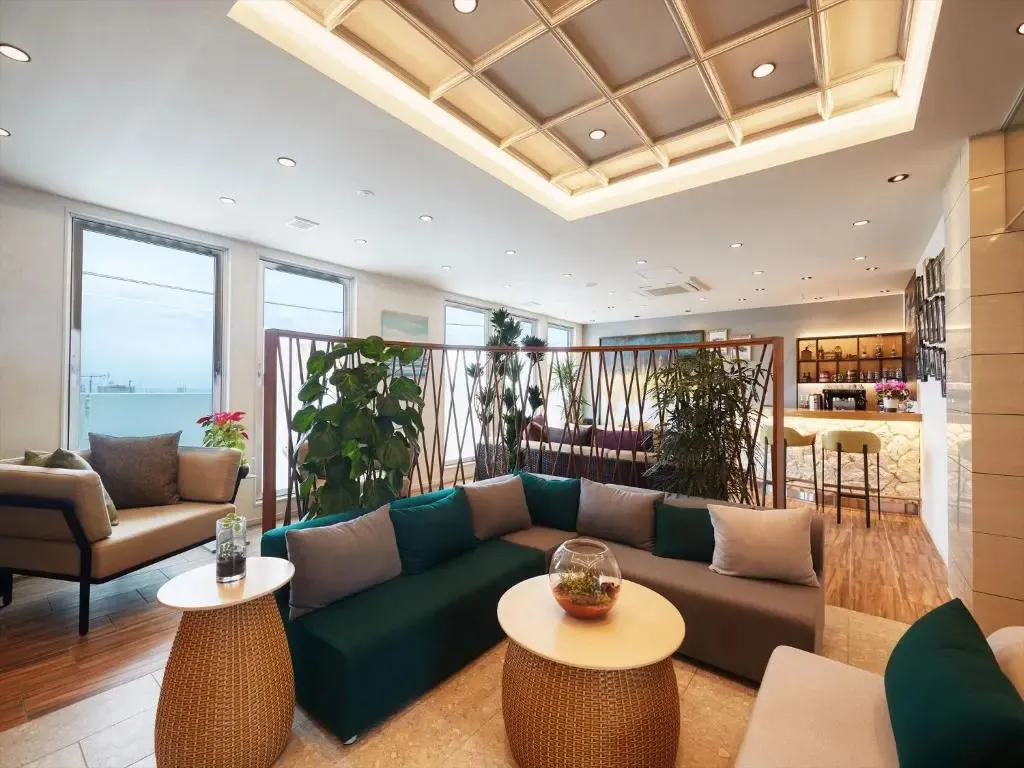 Espace de détente intérieur avec canapés et tables basses près de grandes fenêtres.