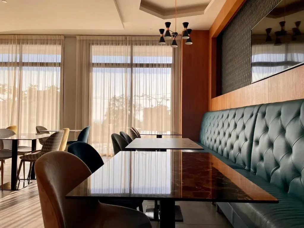 Une salle lumineuse avec des tables et des banquettes confortables près de grandes fenêtres.