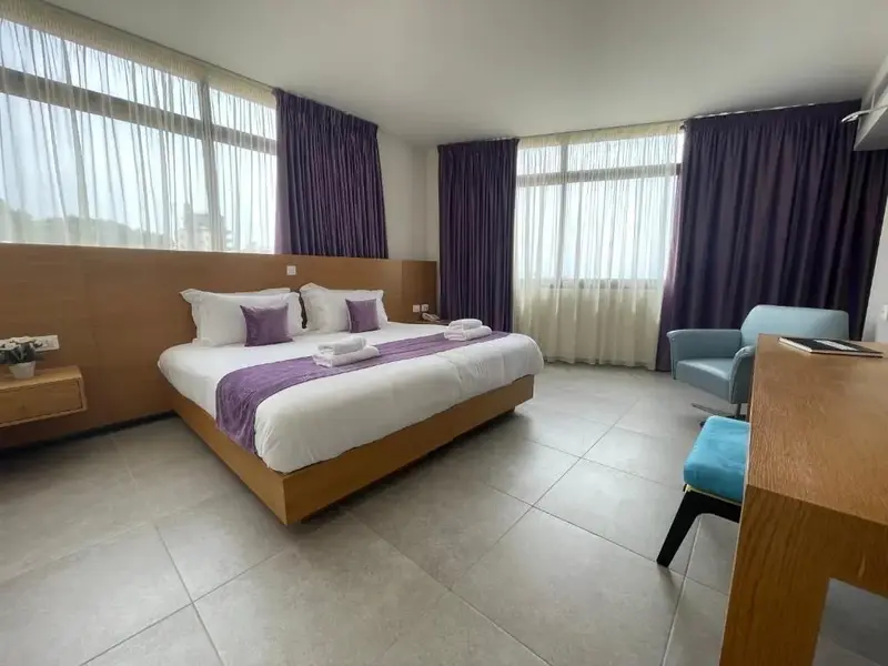 Une chambre lumineuse avec un grand lit et un coin salon.