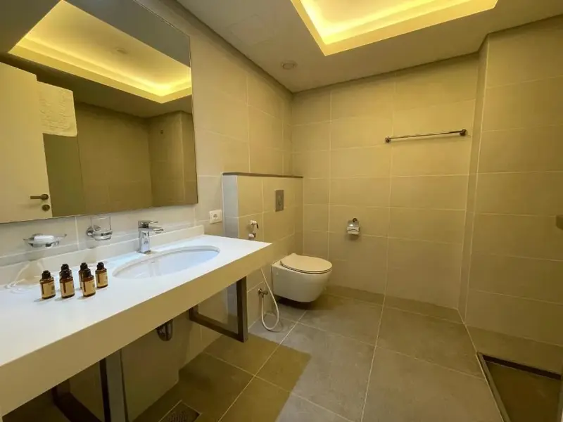 Une salle de bain moderne avec des carreaux beiges et un grand miroir.
