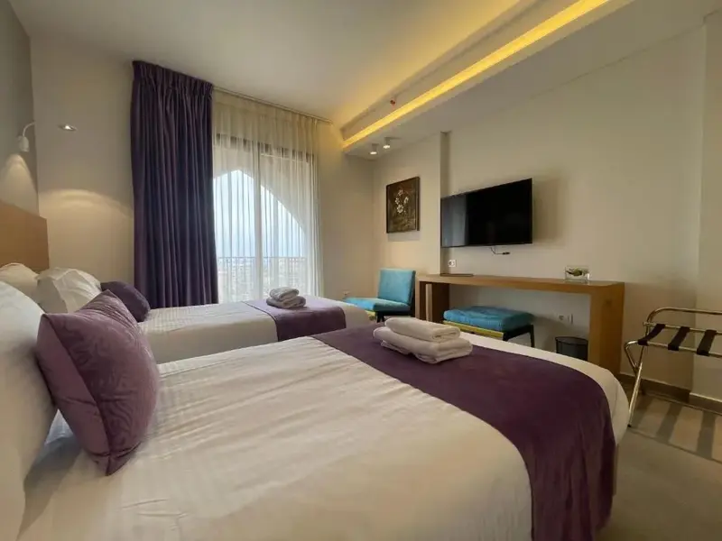Une chambre lumineuse avec deux lits simples et un coin salon.
