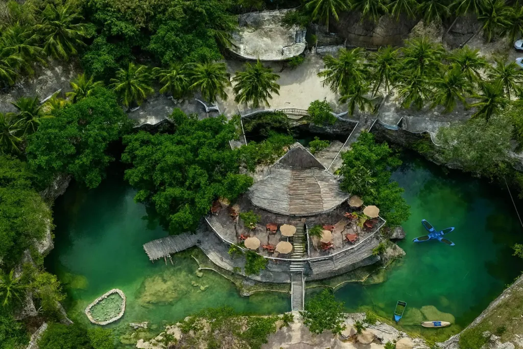Vue aérienne d'un restaurant en plein air entouré de végétation luxuriante et d'une étendue d'eau turquoise.