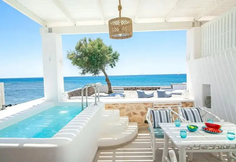 Espace extérieur avec jacuzzi et table à manger face à la mer.
