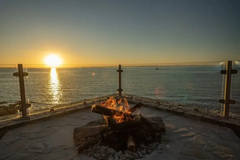 Un foyer extérieur avec vue sur la mer au coucher du soleil.