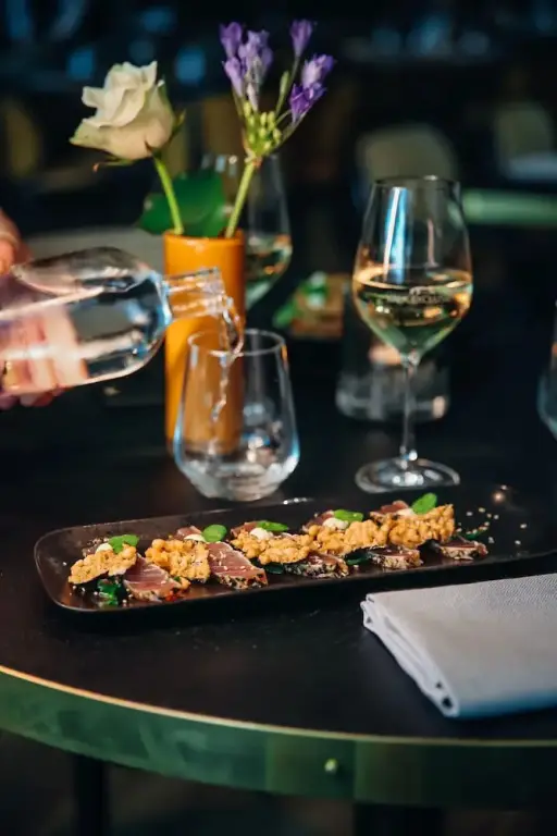 Une table est dressée avec une assiette de nourriture, un verre de vin et une carafe d'eau.