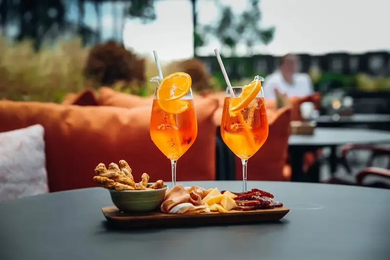 Deux verres orangés accompagnés de collations sur une table sombre.