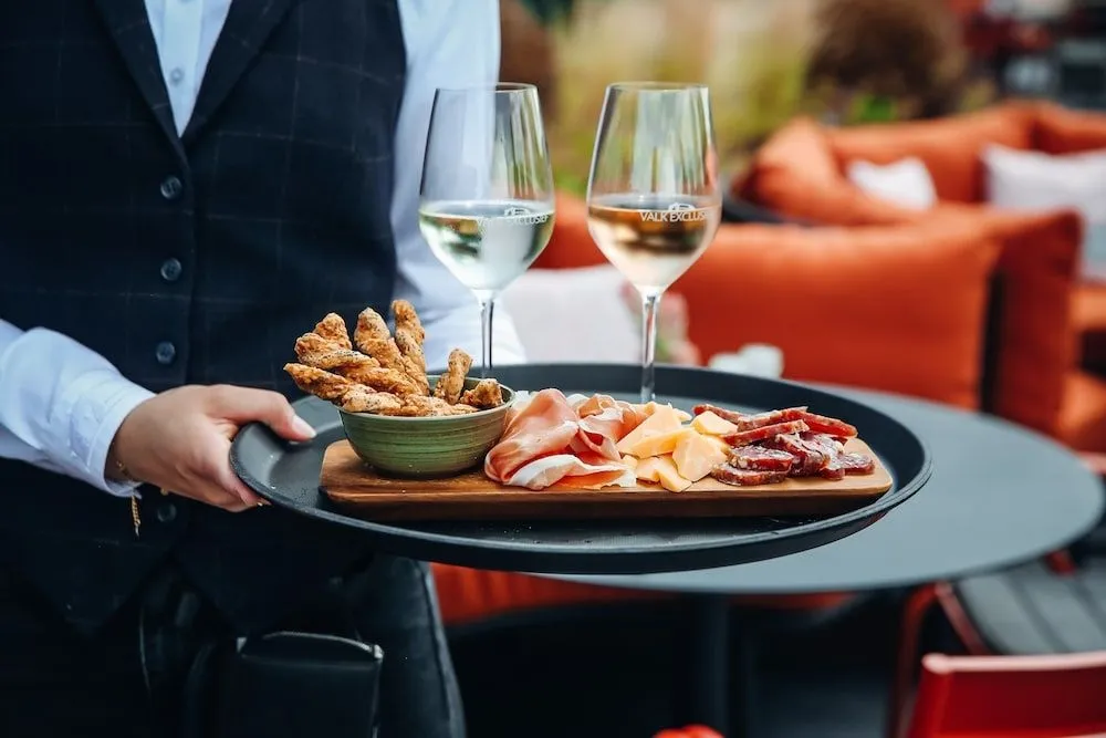Une personne sert des boissons et des amuse-gueules sur un plateau noir.