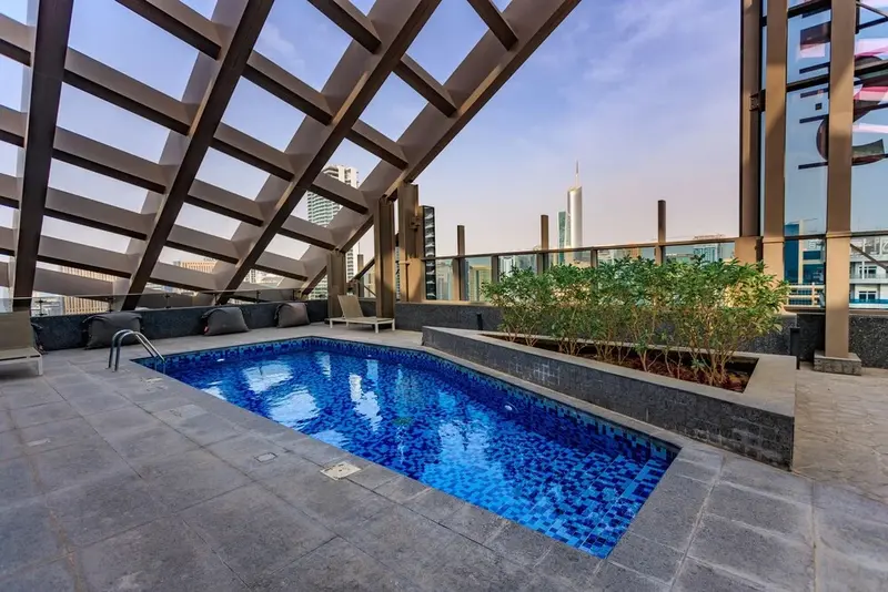 Une piscine rectangulaire sur une terrasse avec des chaises longues et des plantes.