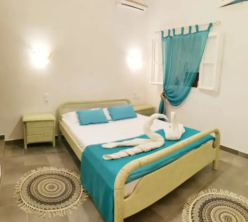Une chambre lumineuse avec un lit recouvert d'une courtepointe turquoise et de décorations en forme de cygnes.