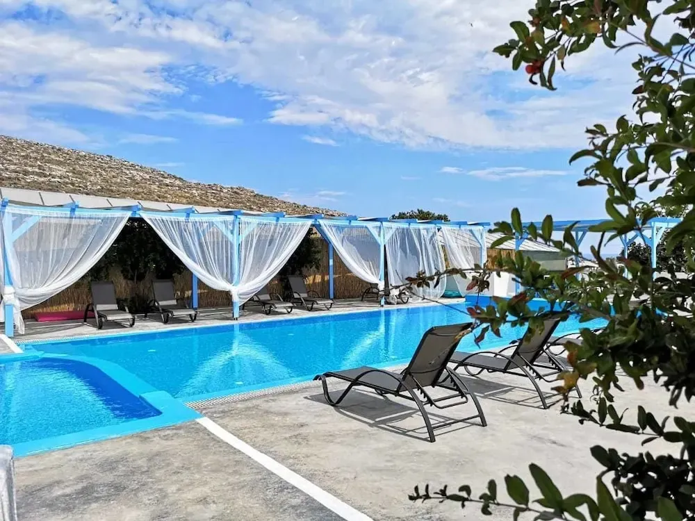 Transats alignés au bord d'une piscine rectangulaire sous une pergola ombragée.