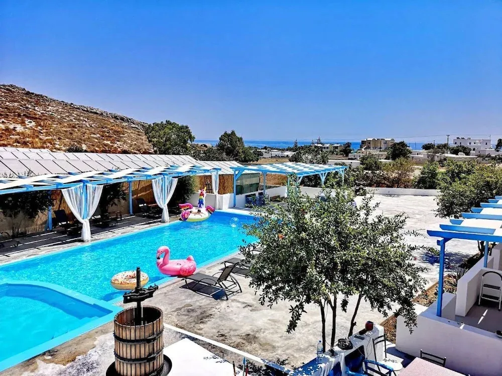 Une piscine rectangulaire avec des transats et un flamant rose gonflable, entourée d'une terrasse ombragée.