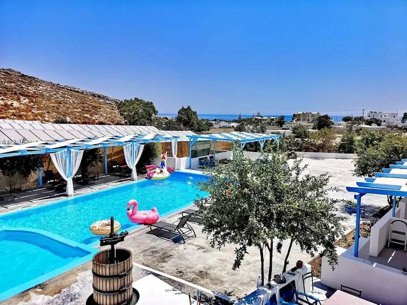 Une piscine rectangulaire avec des transats et un flamant rose gonflable, entourée d'une terrasse ombragée.