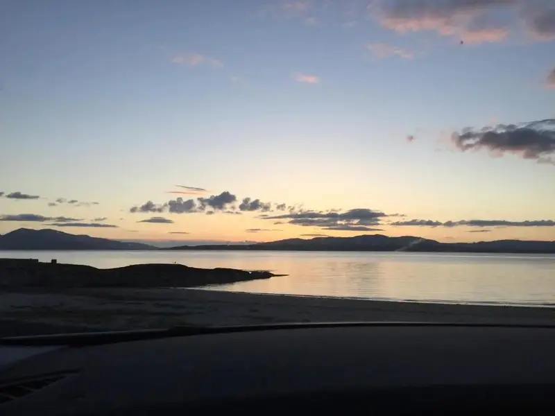 Coucher de soleil sur une plage avec une vue sur les montagnes.