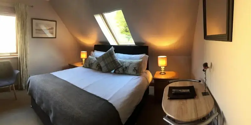 Une chambre mansardée avec un lit double et une petite table.