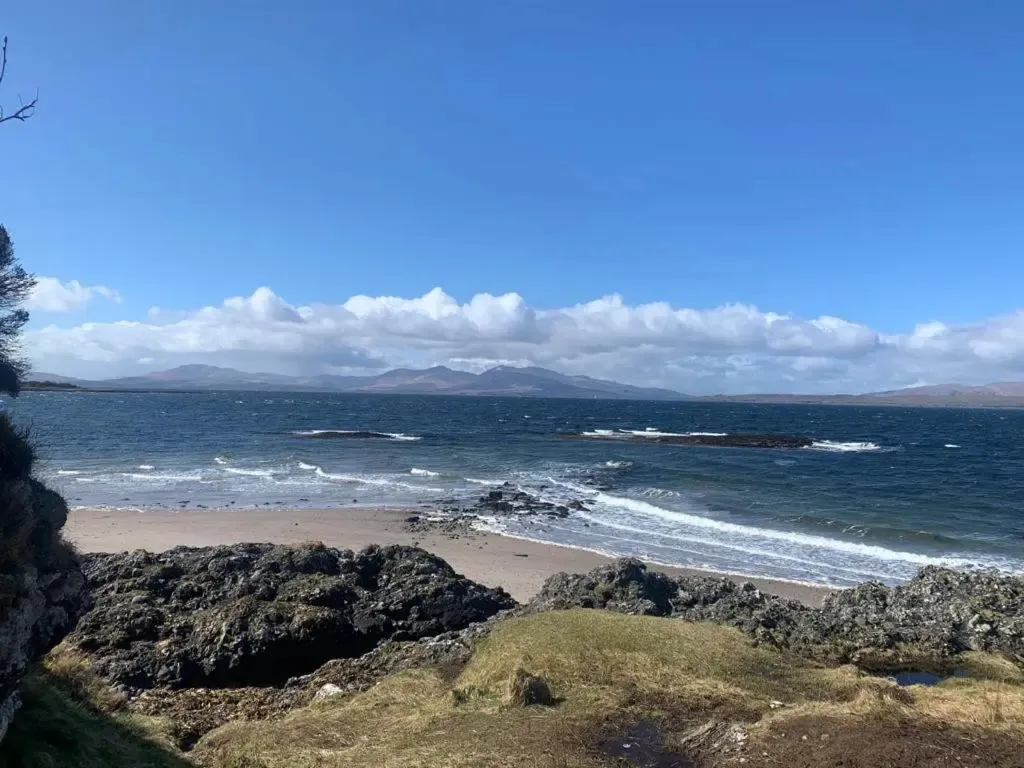 Une plage de sable fin borde une mer bleue sous un ciel nuageux.