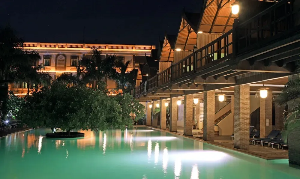 Une piscine illuminée au bord d'un bâtiment éclairé la nuit.
