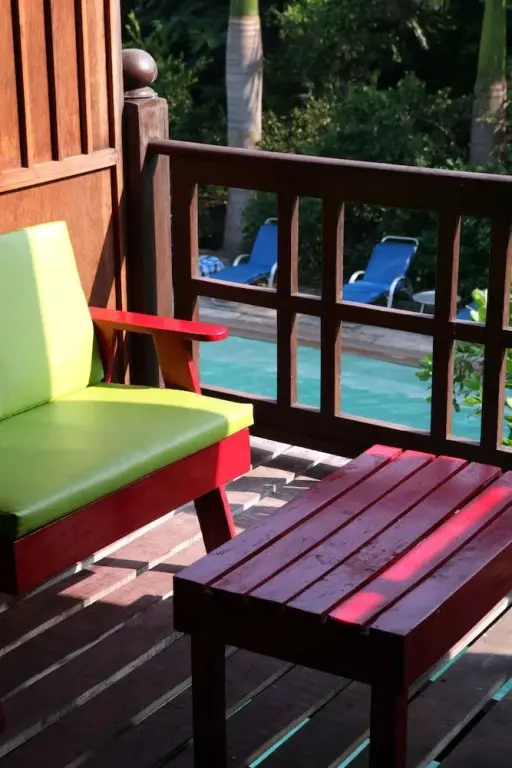 Mobilier de jardin en bois sur une terrasse ensoleillée avec vue sur une piscine.