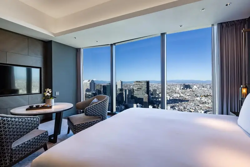 Une chambre lumineuse avec un grand lit et une vue panoramique sur la ville.