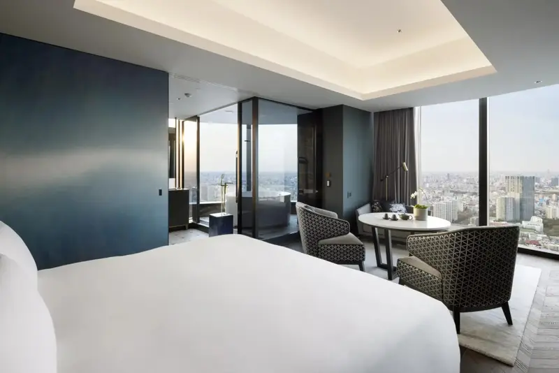 Une chambre moderne avec un grand lit et un coin salon offrant une vue sur la ville.
