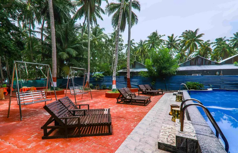 Terrasse avec chaises longues et balancelles près d'une piscine.