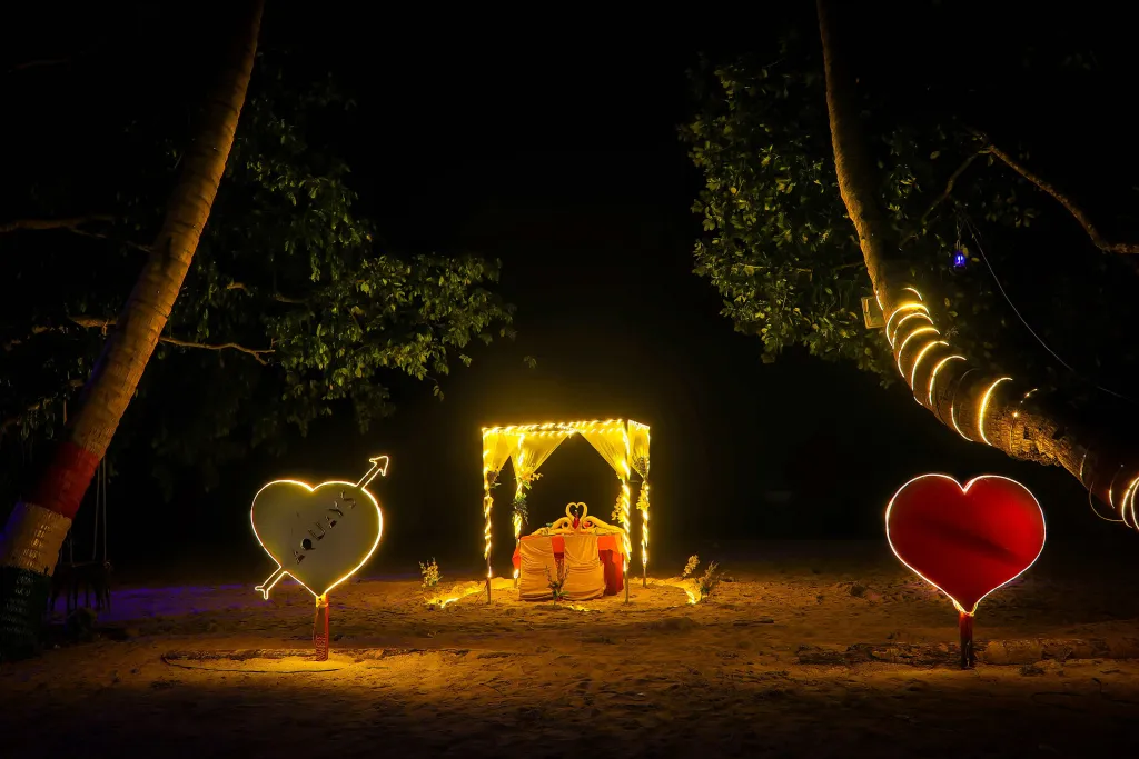 Une table romantique éclairée par des guirlandes lumineuses sur une plage nocturne.