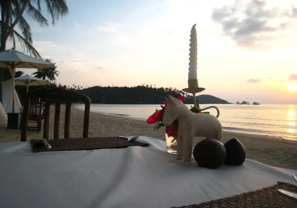 Une table dressée sur le sable au coucher du soleil.