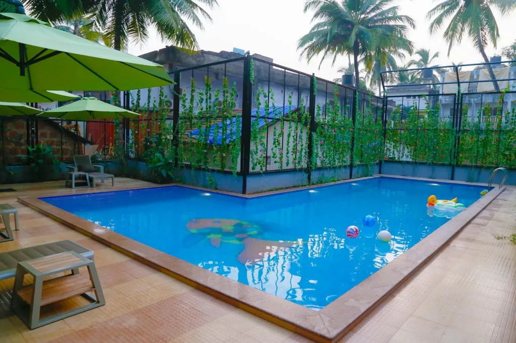 Une piscine rectangulaire entourée d'une terrasse avec des transats et des parasols.