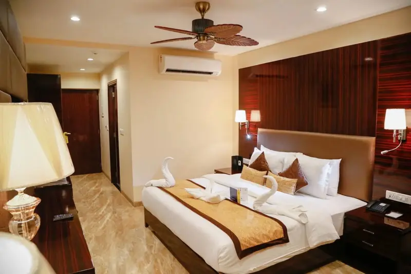 Une chambre lumineuse avec un grand lit décoré de serviettes en forme de cygnes.