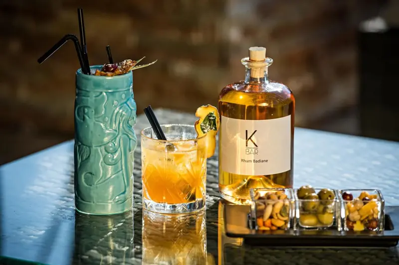 Deux cocktails et une bouteille de rhum sont présentés sur une table.