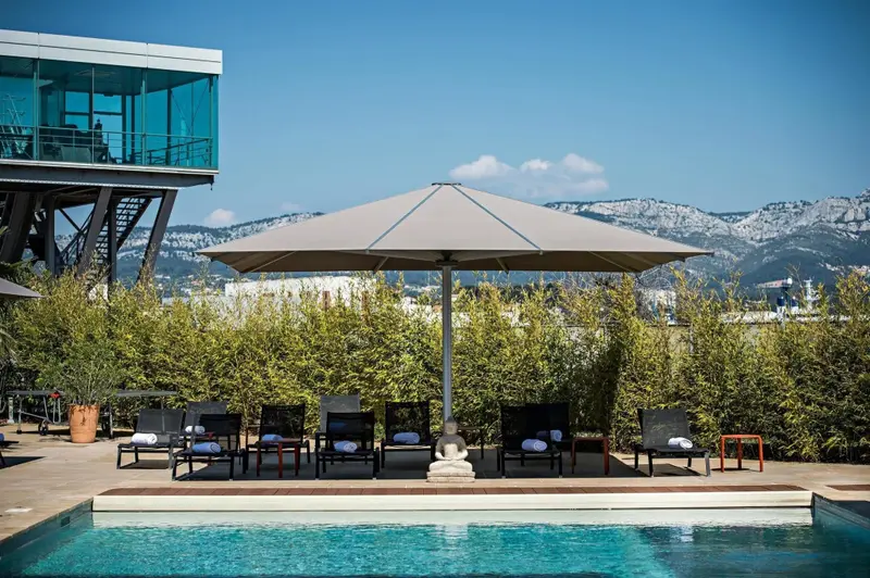 Transats et parasol au bord d'une piscine avec vue sur les montagnes.