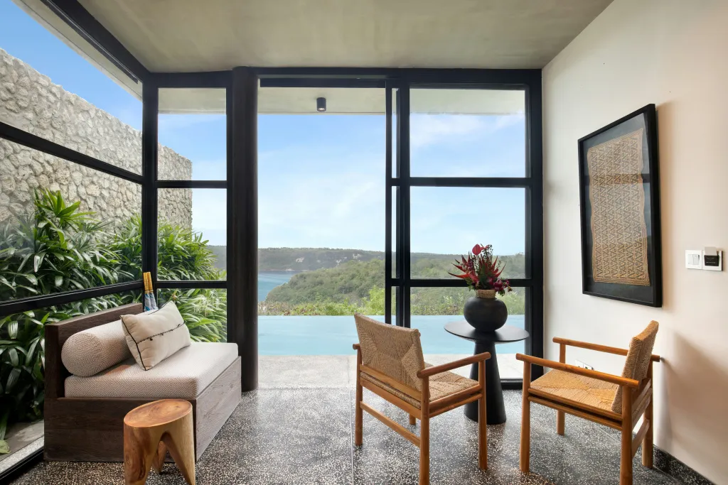 Espace de détente intérieur avec vue sur la mer et la végétation.