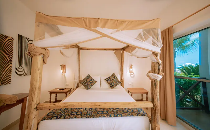 Une chambre lumineuse avec un lit à baldaquin et une vue sur la végétation.