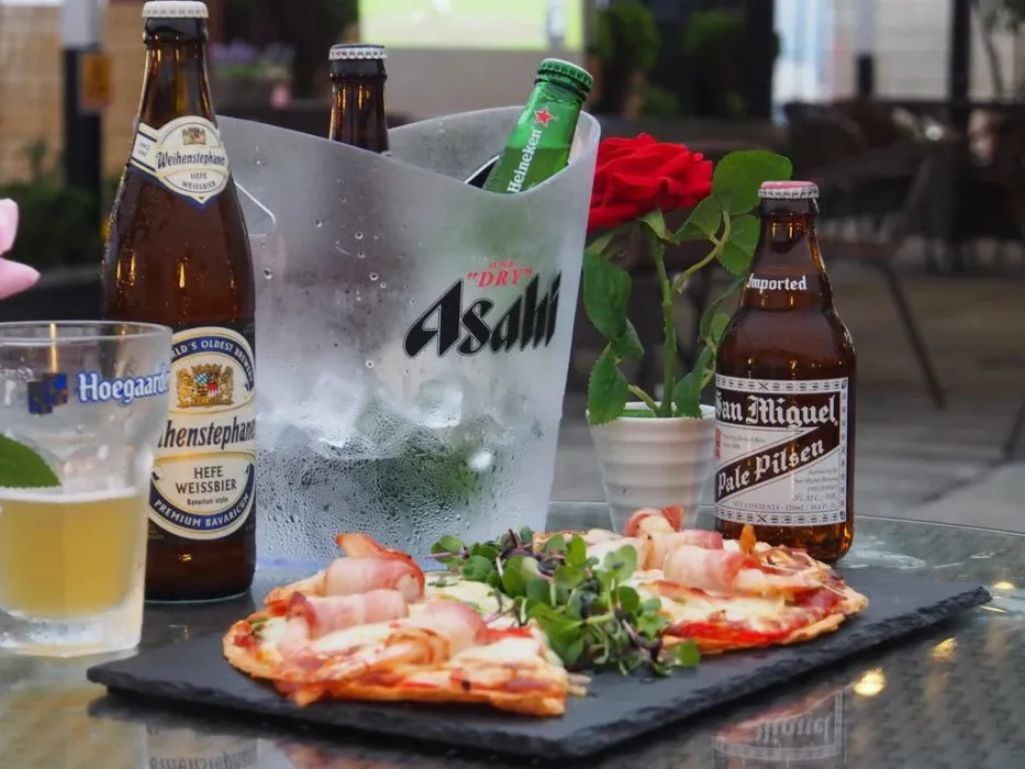 Des pizzas et des bouteilles de bière sont présentées sur une table.