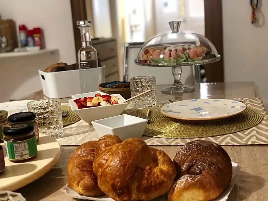 Une table est dressée avec des viennoiseries, des fruits et des confitures.