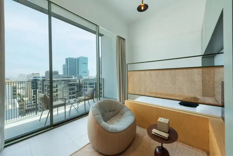 Espace de détente intérieur avec vue sur la ville depuis une large baie vitrée.