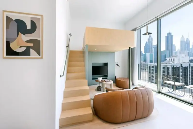 Un espace de vie moderne avec un canapé incurvé et un escalier menant à une mezzanine.