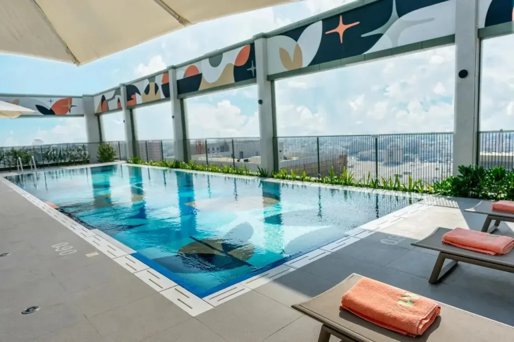 Une piscine rectangulaire avec des transats et une vue sur la ville.