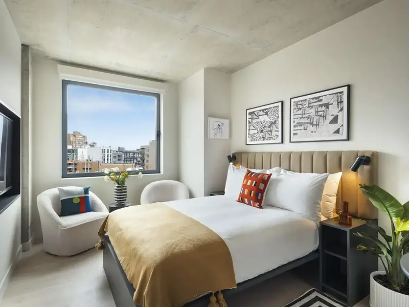 Une chambre lumineuse avec un grand lit et un coin salon près d'une fenêtre.