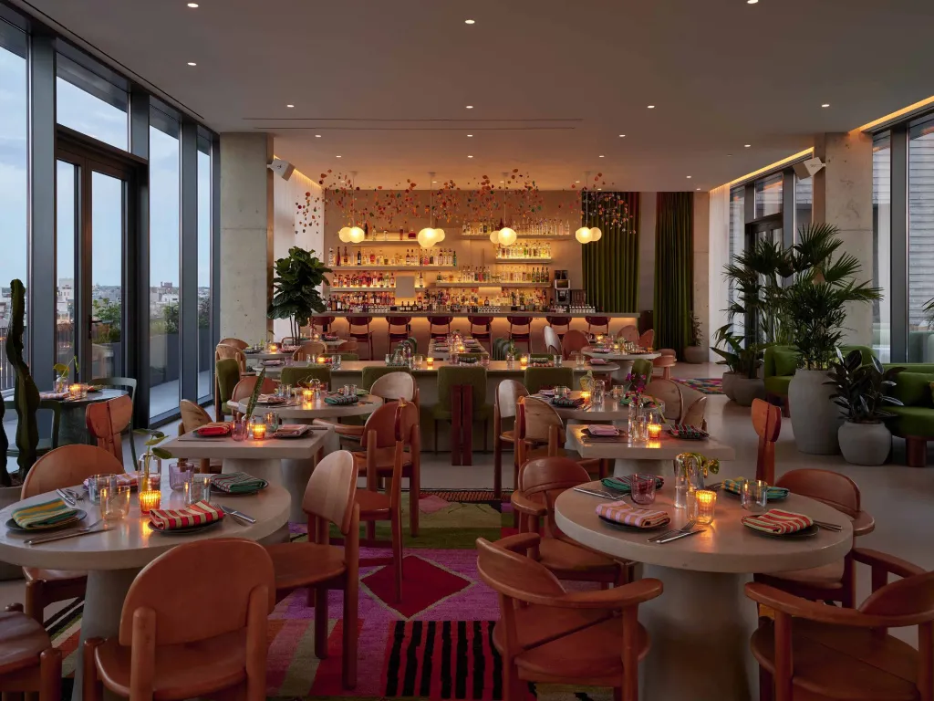 Une salle lumineuse avec des tables et des chaises, un comptoir de bar et des plantes.
