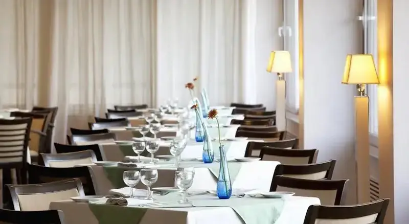 Une salle lumineuse avec des tables dressées pour un repas.