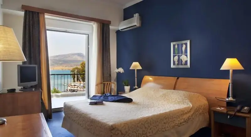 Une chambre lumineuse avec un lit fait et une vue sur la mer par une baie vitrée.
