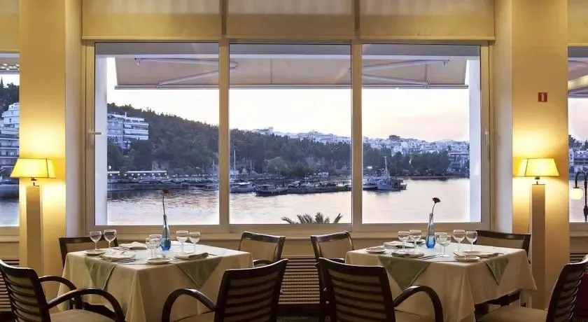 Une salle à manger lumineuse offre une vue sur un port et une colline.