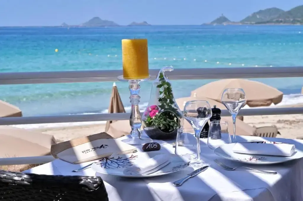 Table dressée en extérieur avec vue sur la mer et la plage.