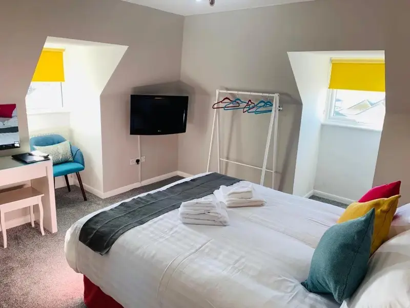 Une chambre lumineuse avec un lit recouvert d'une couverture et de coussins colorés.