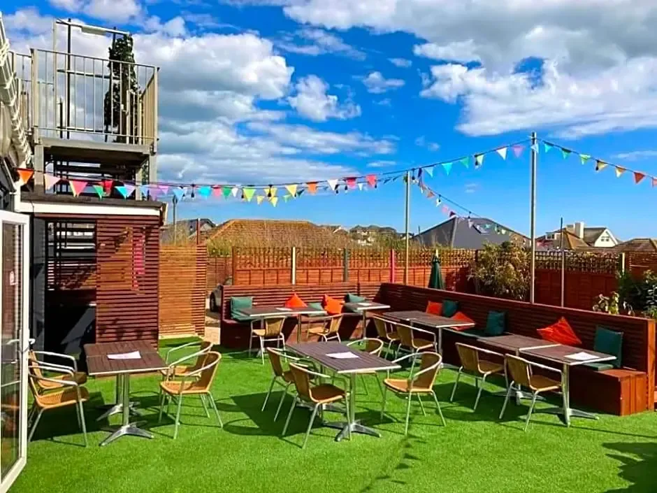 Terrasse aménagée avec tables et chaises sous guirlandes colorées, avec une vue sur la ville.
