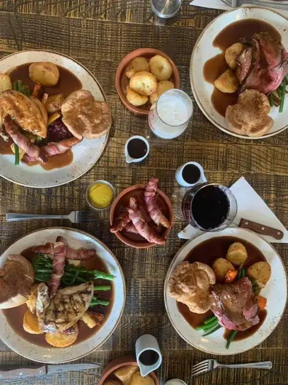 Assiettes garnies de viande, de légumes et de sauce, accompagnées de boissons et de condiments.