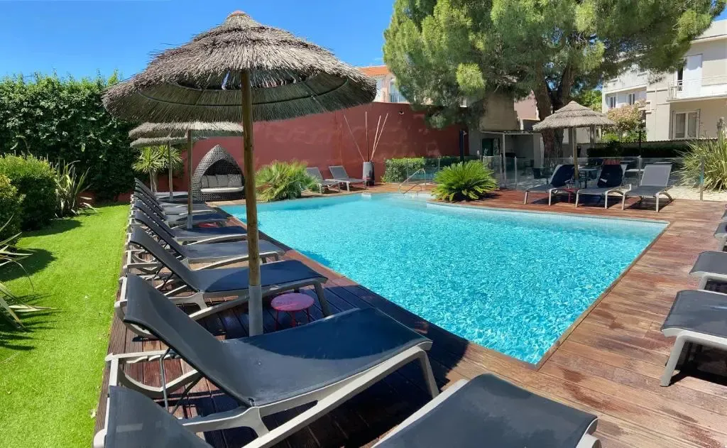 Transats alignés au bord d'une piscine rectangulaire ensoleillée.
