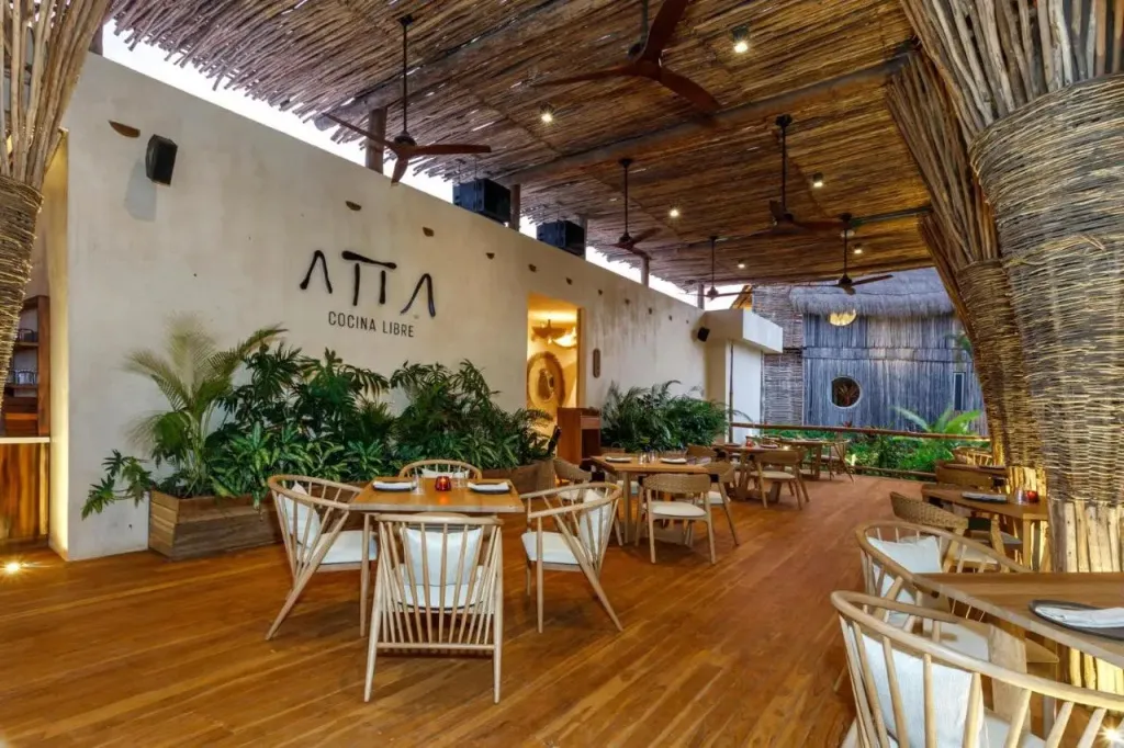 Une salle de restaurant lumineuse avec des tables en bois et des chaises en rotin.
