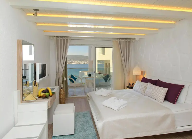 Une chambre lumineuse avec un lit et un accès à un balcon vue mer.