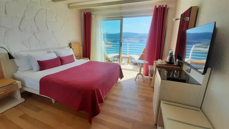 Une chambre lumineuse avec un grand lit donnant sur une vue mer.